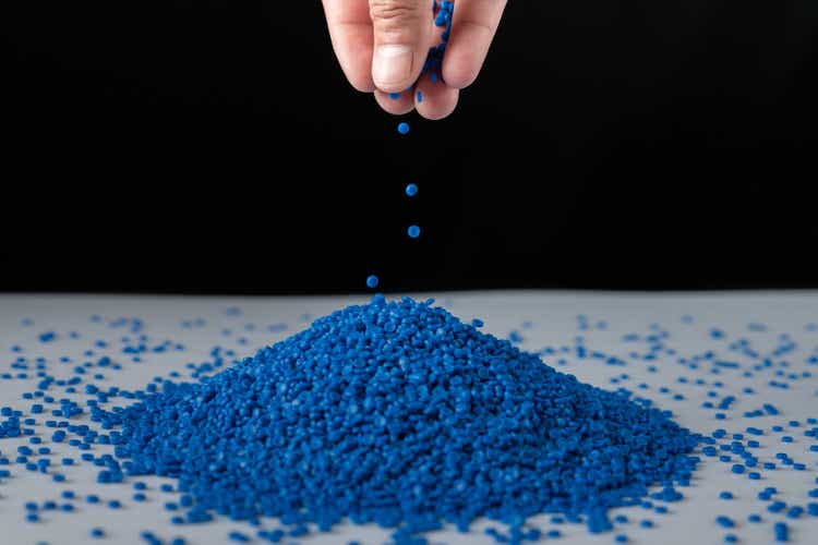 Blue plastic beads on wood background, Polymers bead or polymer resin, polymer pallet, Product from petrochemical plants. granules polymer, Concept roof of house is made of polymer plastic.