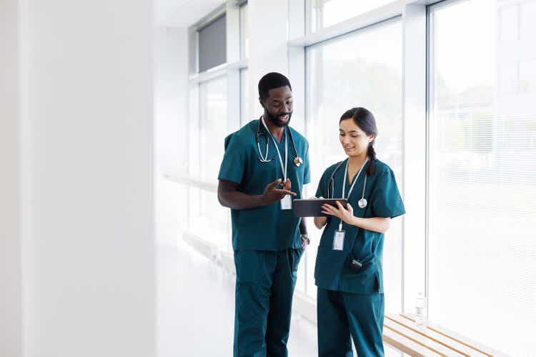 Two doctors in hospital hallway discussing electronic patient record