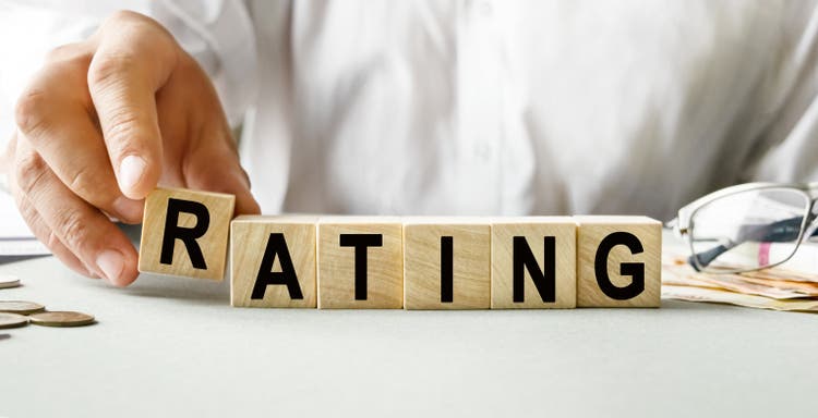 RATING inscription on the texture of wooden cubes. A business man holds a cube in his hand. An inscription on a financial, business or economic theme.