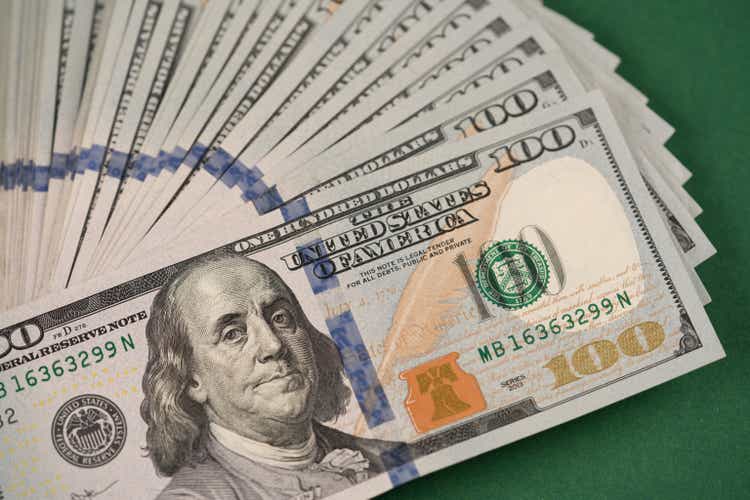 Close up of stack of one hundred dollar bills on a dark green background. cash Money. Financial growth and business concept