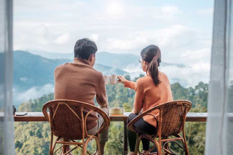 Couple tourist drinking coffee and eating breakfast against mountain view at countryside home or homestay in the morning. Vacation, together travel, honeymoon, blogger, journey and trip concept