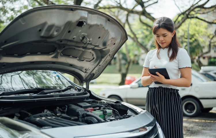 An Asian Insurance adjuster inspecting damage to vehicle