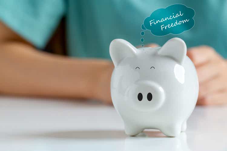 Happy smiley face piggy bank with text label "financial freedom" Saving money for financial independence or financial freedom concept.
