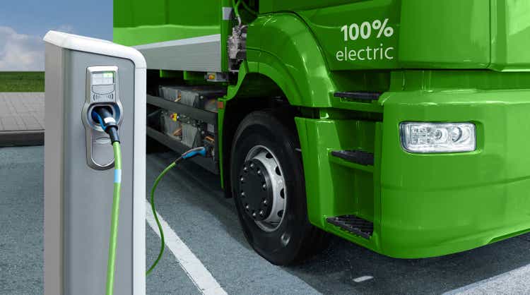 Green electric truck is charged from the charging station
