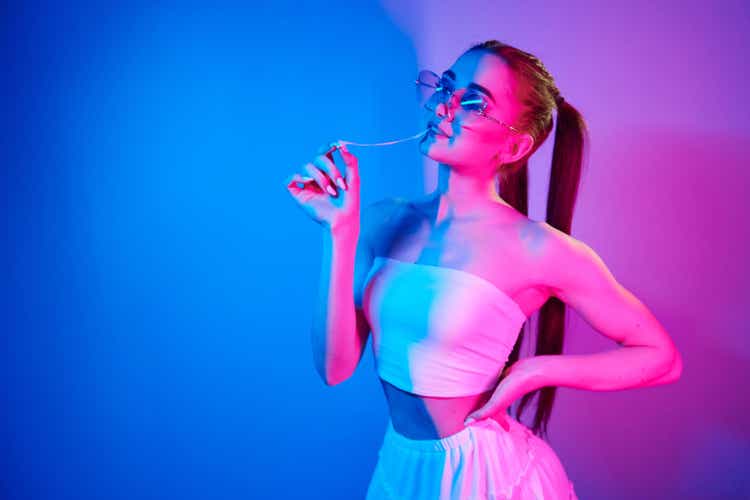 Positive emotions. Fashionable young woman standing in the studio with neon light