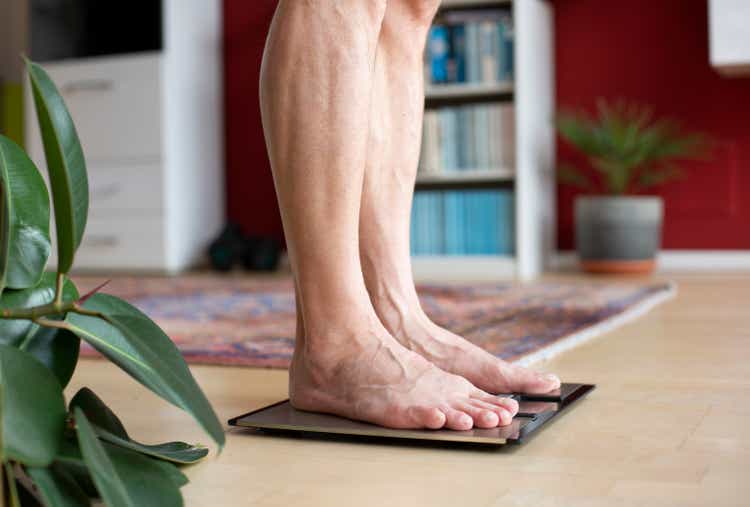 Man standing on weight scale, low section