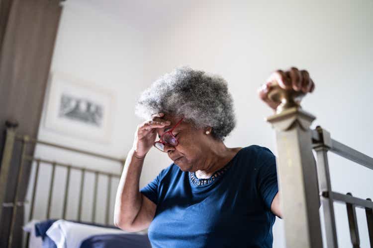 Senior woman with headache sitting in the bed at home