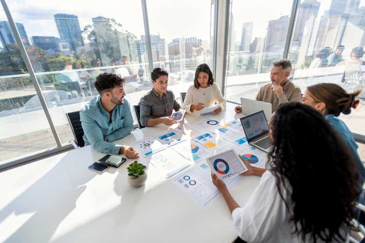 Multiracial people working with paperwork at boardroom table during business presentation or seminar.