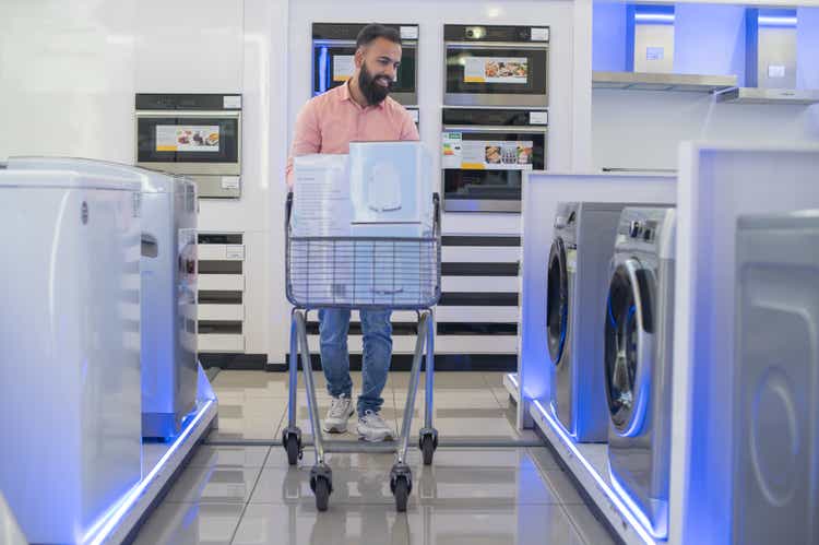 A young man looking at washing machines in an appliance store.