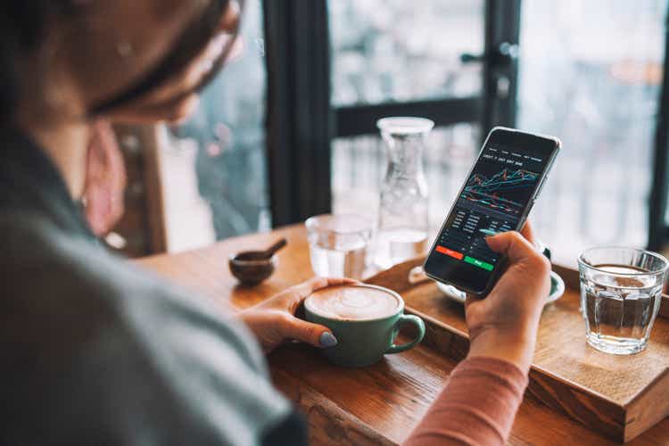 Woman using smartphone buying cryptocurrency in a coffee shop, blockchain investment, decentralization and stock market concept.