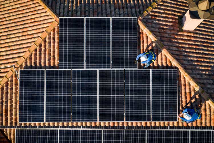 aerial view of Two workers installing solar panels on a rooftop