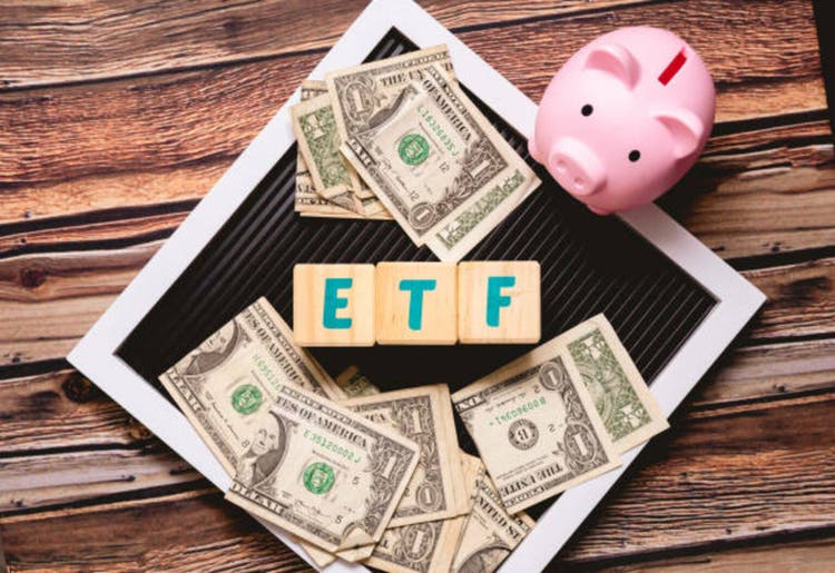 Exchange Traded Fund Initials ETFS on wooden blocks written in English with American accounts for US dollar and pigs in the image. Photo with the best view.