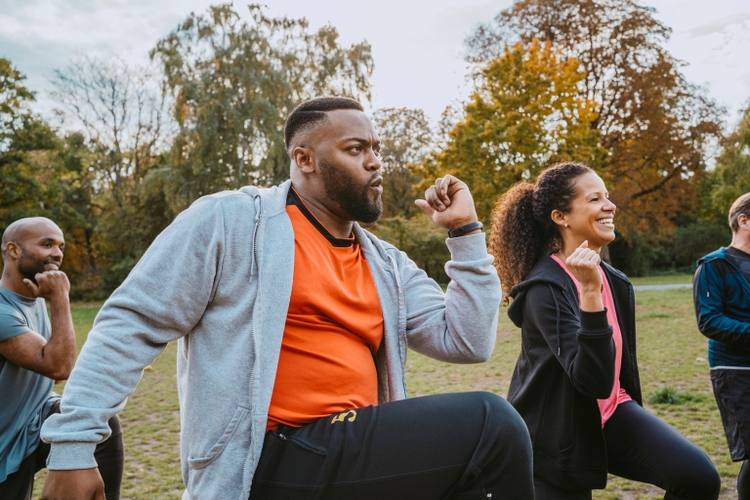 Multiracial male and female friends exercising in park