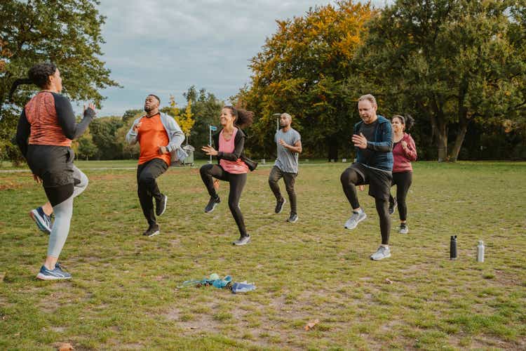 Female instructor teaching running exercise to men and women in park