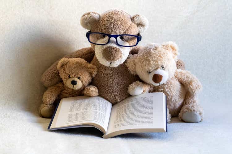 Three teddy bears reading a book