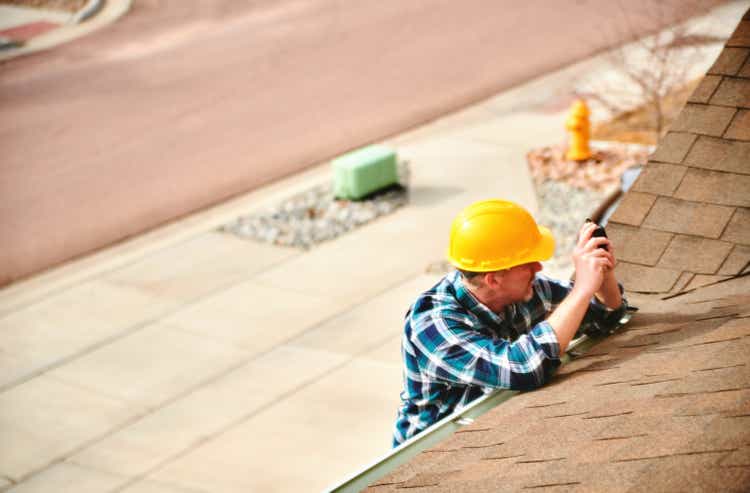 Insurance agent or roofer on roof assessing damage to a roof