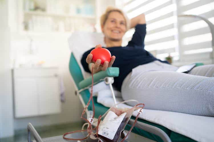 Happy woman is laying down while donating her blood