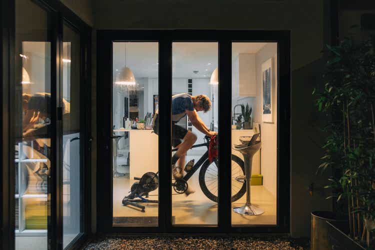 Man using his indoor bike turbo trainer at home in the evening