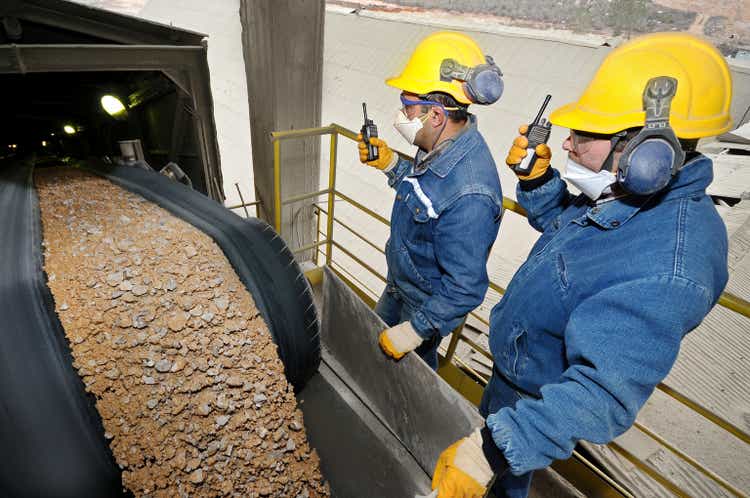 Two specialists examining load at sand conveyor line