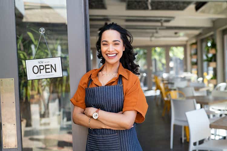 Successful small business owner standing at cafe entrance