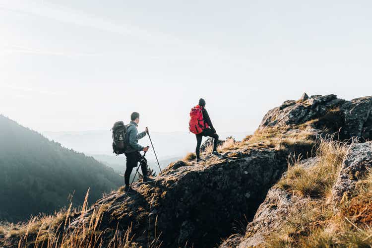 Young couple backpack up a mountain summit