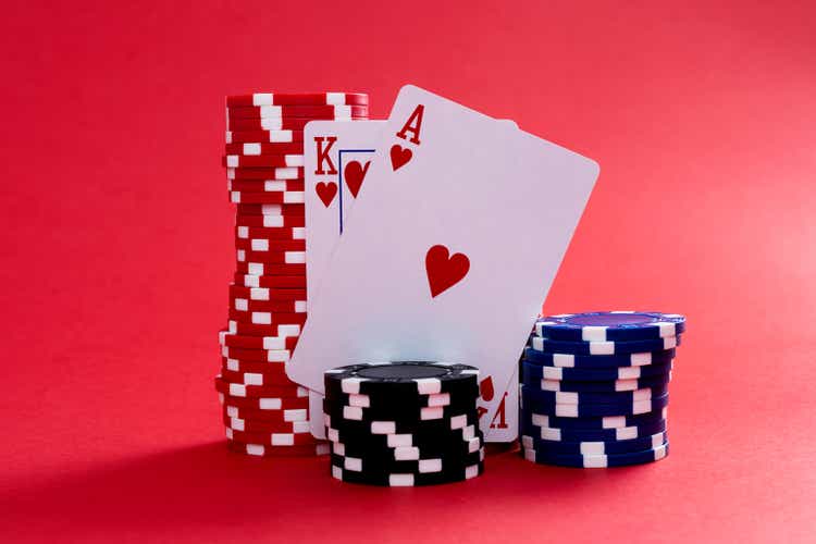 Gambling chips and playing cards on red background.
