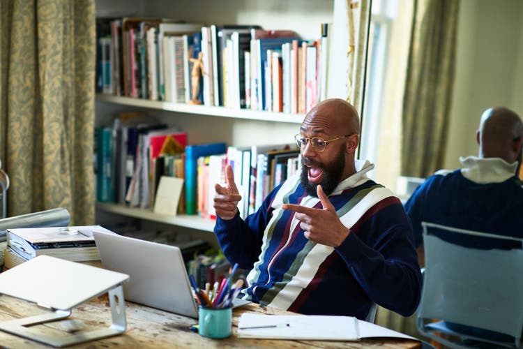 Surprised black businessman on video conference call in home office