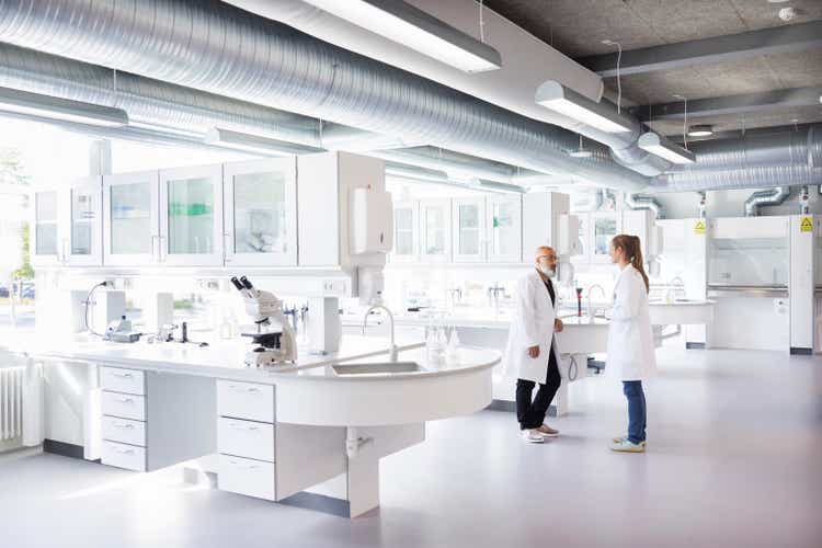 Two scientists in conversation, standing in laboratory