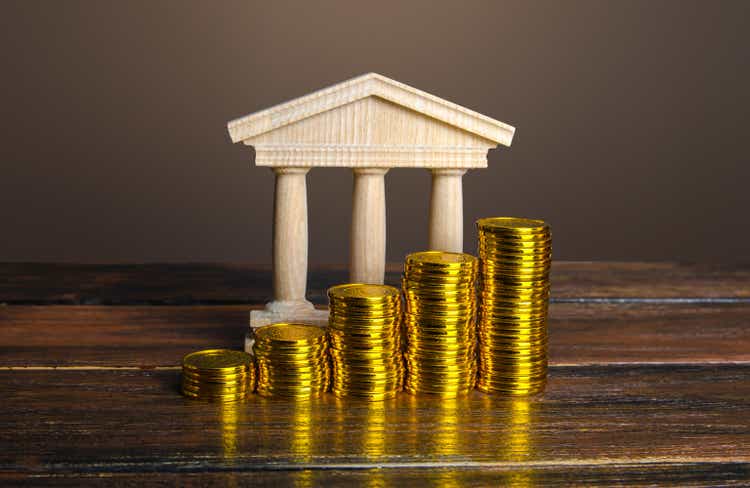 Bank building and increasing stacks of coins. Profitability of deposits and favorable rates for depositors, loyalty programs. Income growth. Increasing taxes collected. Budgeting. Monetary policy.