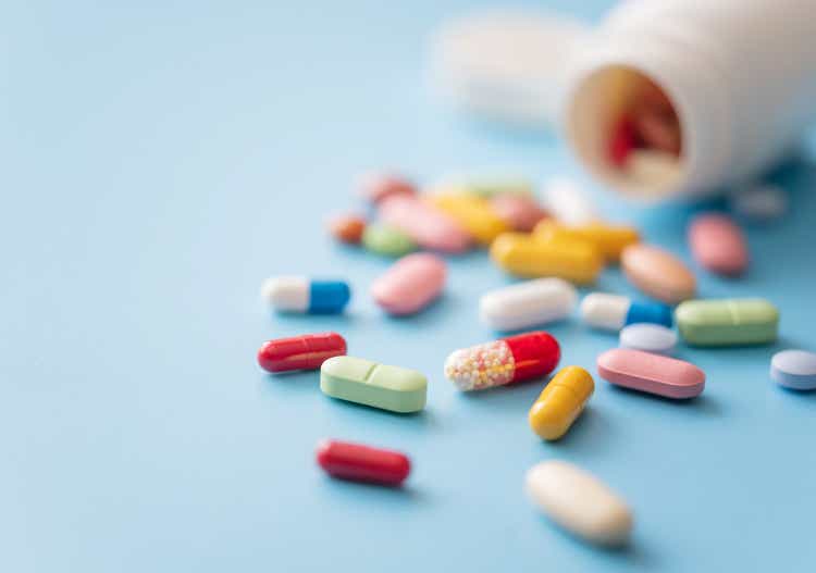 Разноцветные таблетки, разбросанные из белого пластикового контейнера для лекарств