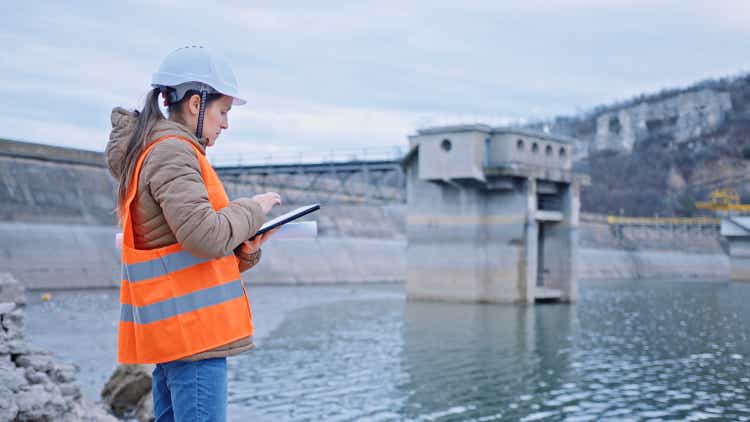 Female engineer working in hydroelectric dam. Ecology orientated. Renewable energy systems.