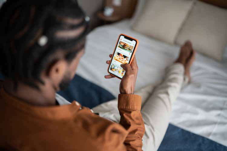 Young man ordering food online with smartphone at home