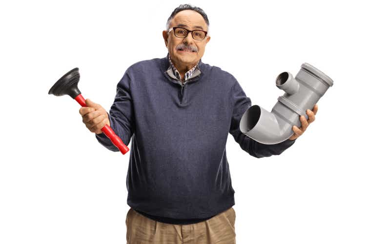 Confused mature man holding a pipe and a toilet plunger