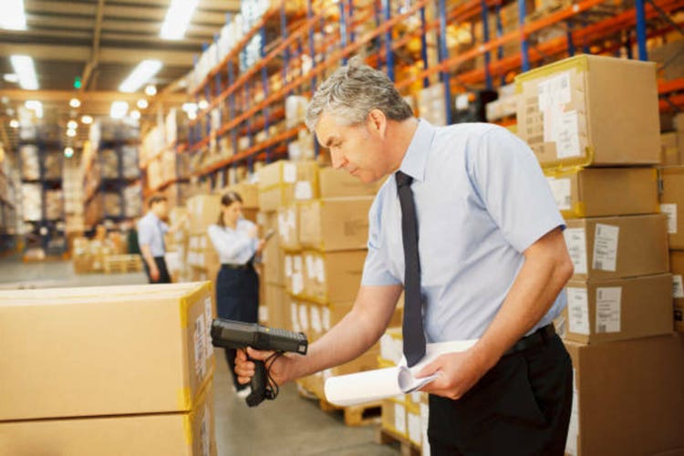 Businessman scanning shipping box in warehouse