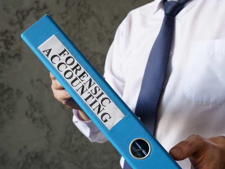 Blue folder with info about forensic accounting in the hands.