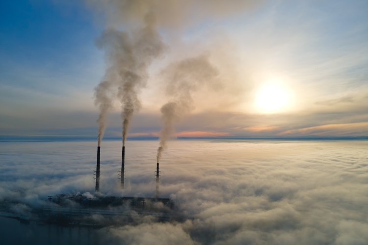 Aerial view of coal power plant high pipes with black smoke moving up polluting atmosphere at sunset