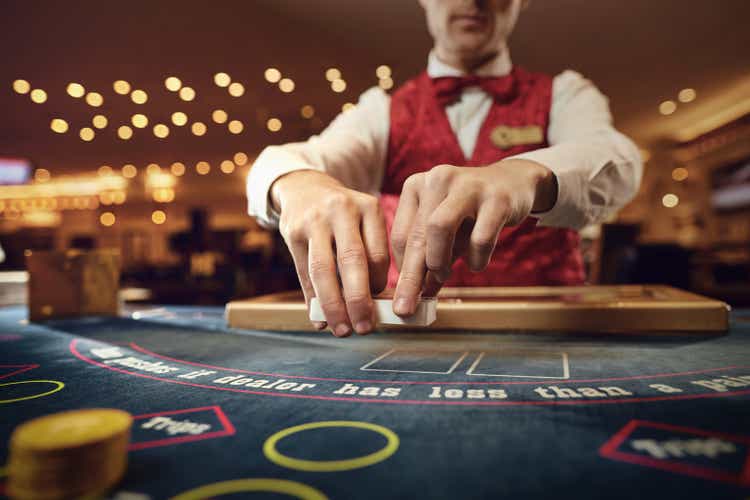 Croupier holds poker cards in his hands at a table in a casino.
