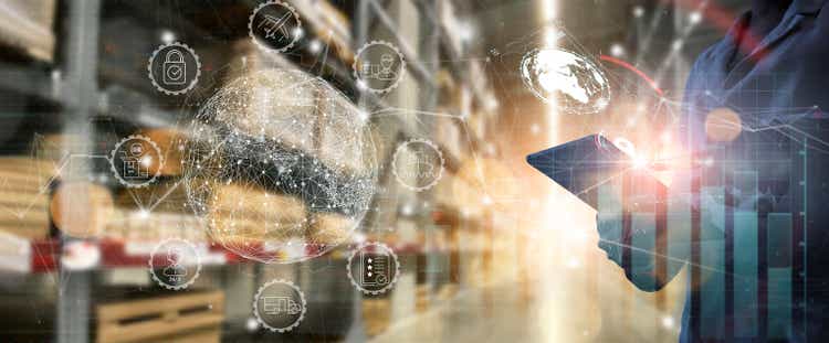 Business Workers using digital tablet computer cargo and tracking delivery for Transportation and global network of smart logistics in blur warehouse background.