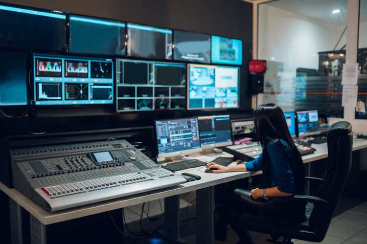 Mujer de mediana edad usando equipo en la sala de control de una estación de televisión