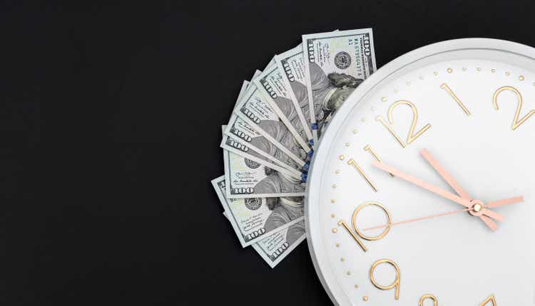 Money with white clock on black background. Top view. Space for text.