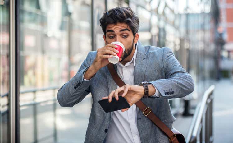 Never don"t be late on business meeting. Worried businessman looking at his watch on the way to office. Business, lifestyle concept