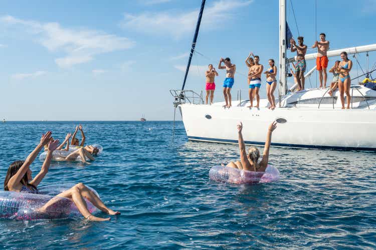 Women floating on inflatable swim rings around yacht