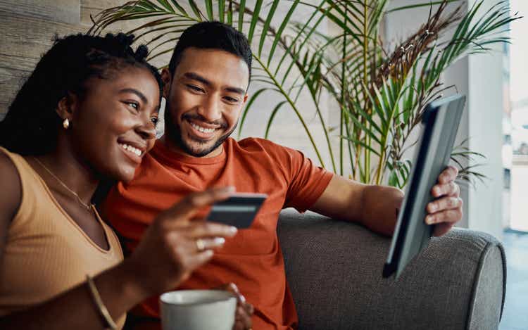 Shot of a young couple sitting together in the living room and using a digital tablet for online shopping