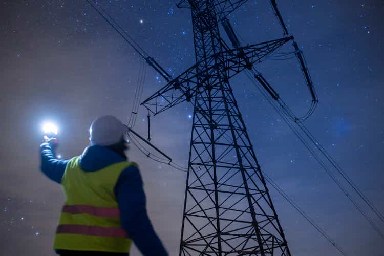 High voltage engineer working at night on the field. Sustainable energy.