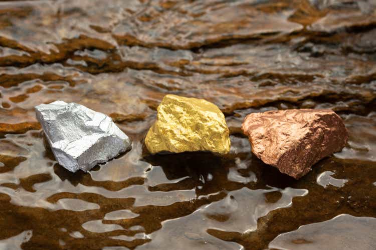 Ingots of pure gold, silver and copper on a rocky ground with flowing water. , valuable minerals