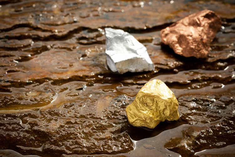 Ingots of pure gold, silver and copper on a rocky ground with flowing water. , valuable minerals