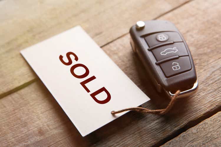 Car auction Sold out concept. Vehicle security key with tag on the wooden background