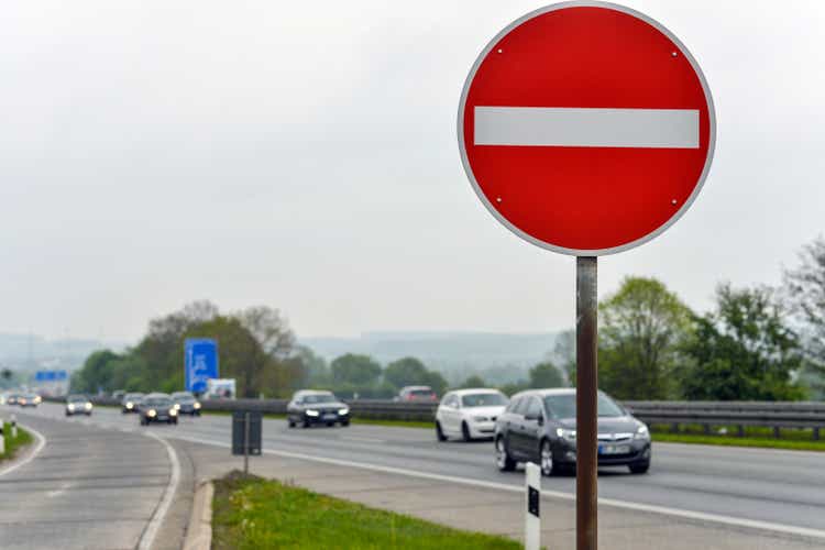 Concept wrong exit on the highway: View of a german Autobahn highway against the direction of traffic with a stop sign in the foreground, several cars