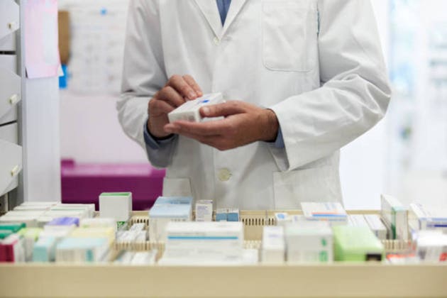 A pharmacist is organizing pillboxes in a drugstore drawer.