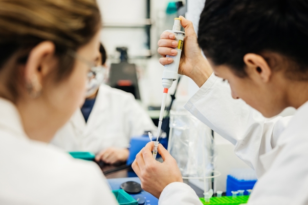 Two Medical Students Using Pipette To Dispense Fluid Accurately